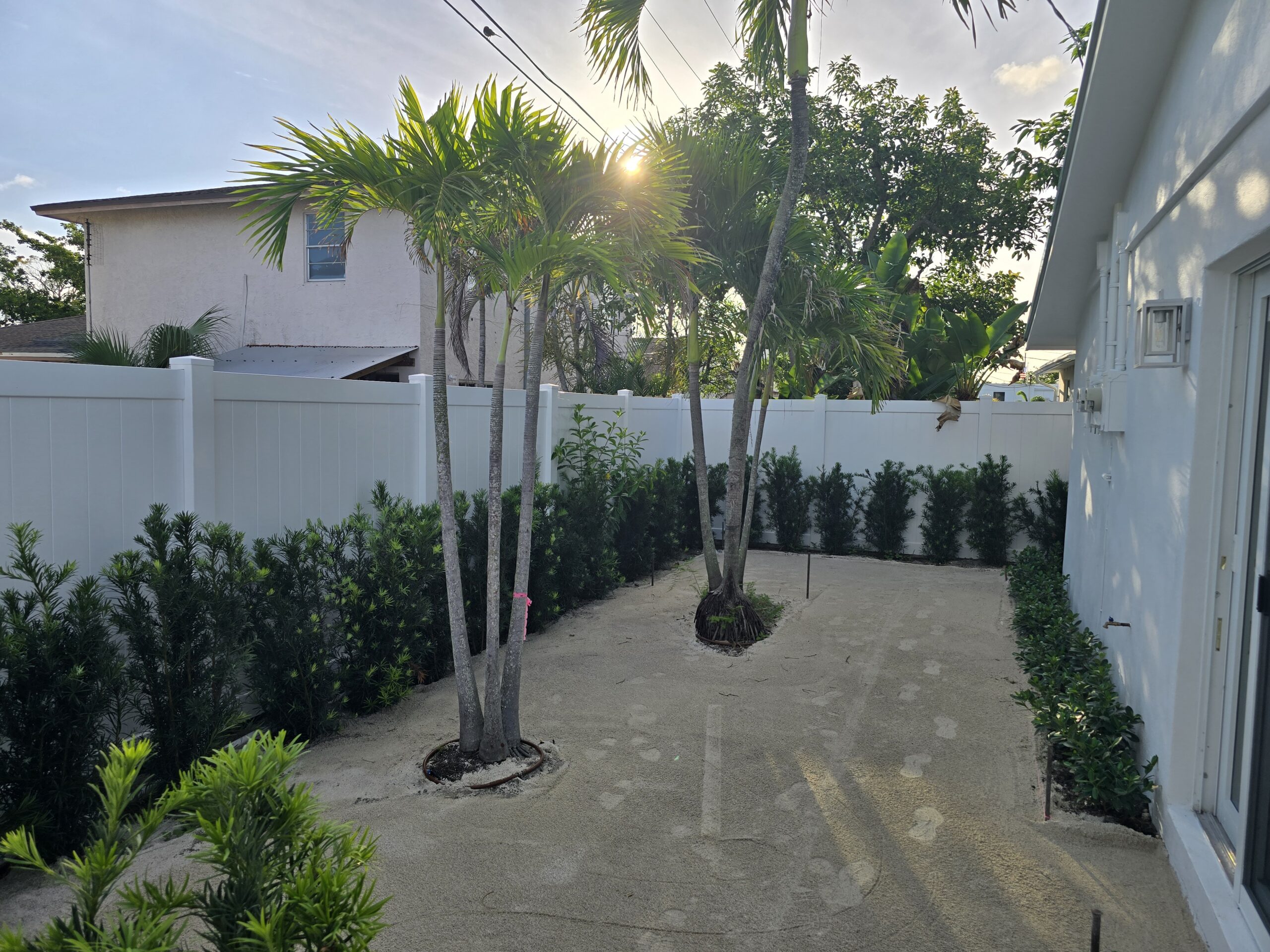 White PVC privacy fence surrounding a landscaped backyard in Palm Beach Island, Florida.
